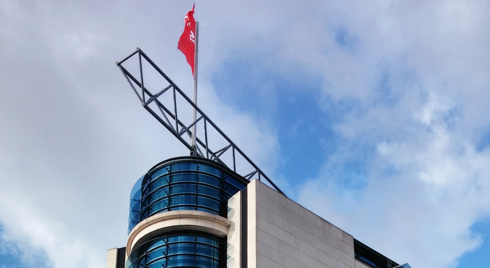 Spitze des Willi-Brandt-Hauses vor leicht bewölktem Himmel.