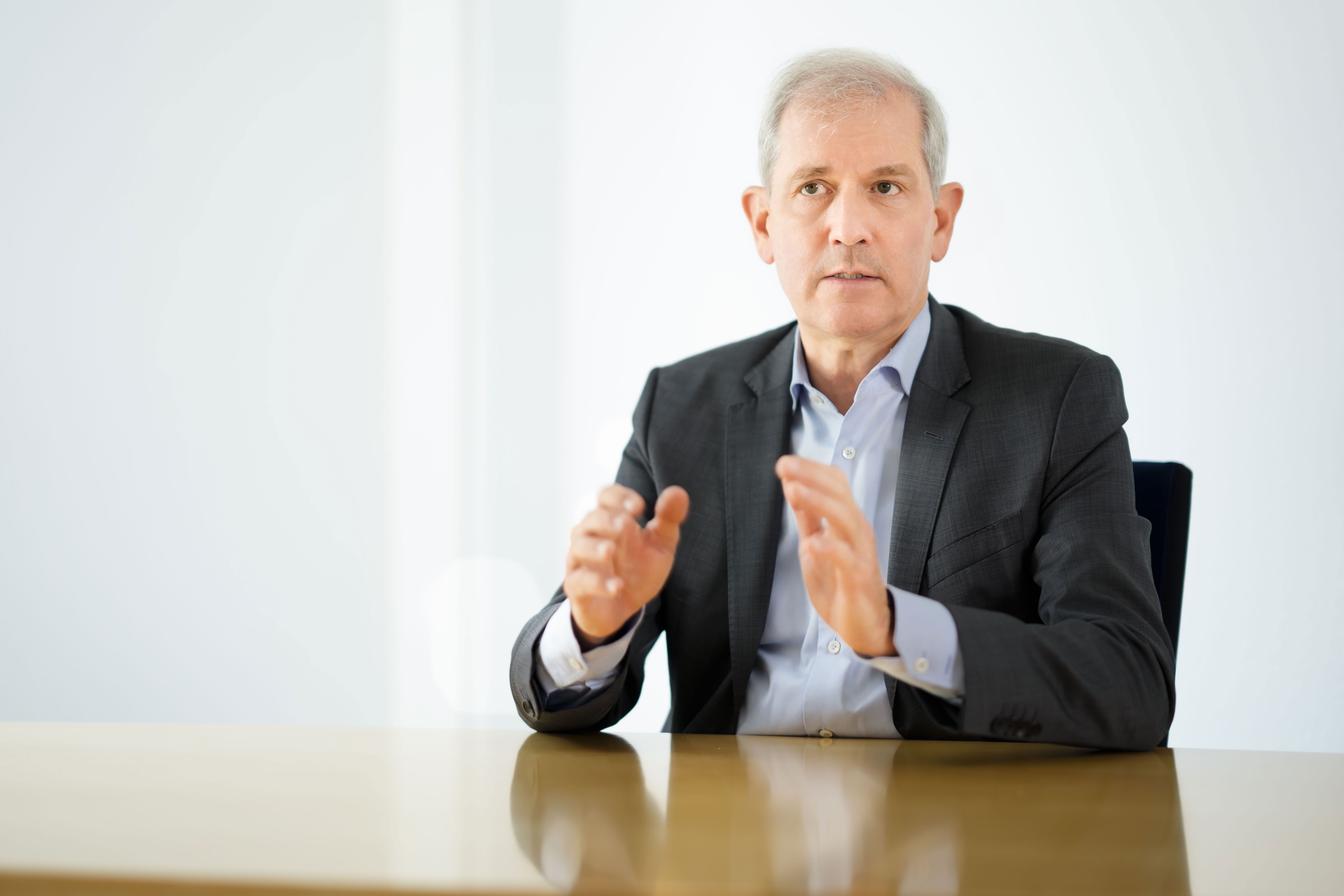 Porträtfoto von Jens Scholz, am Tisch sitzend, gestikulierend.