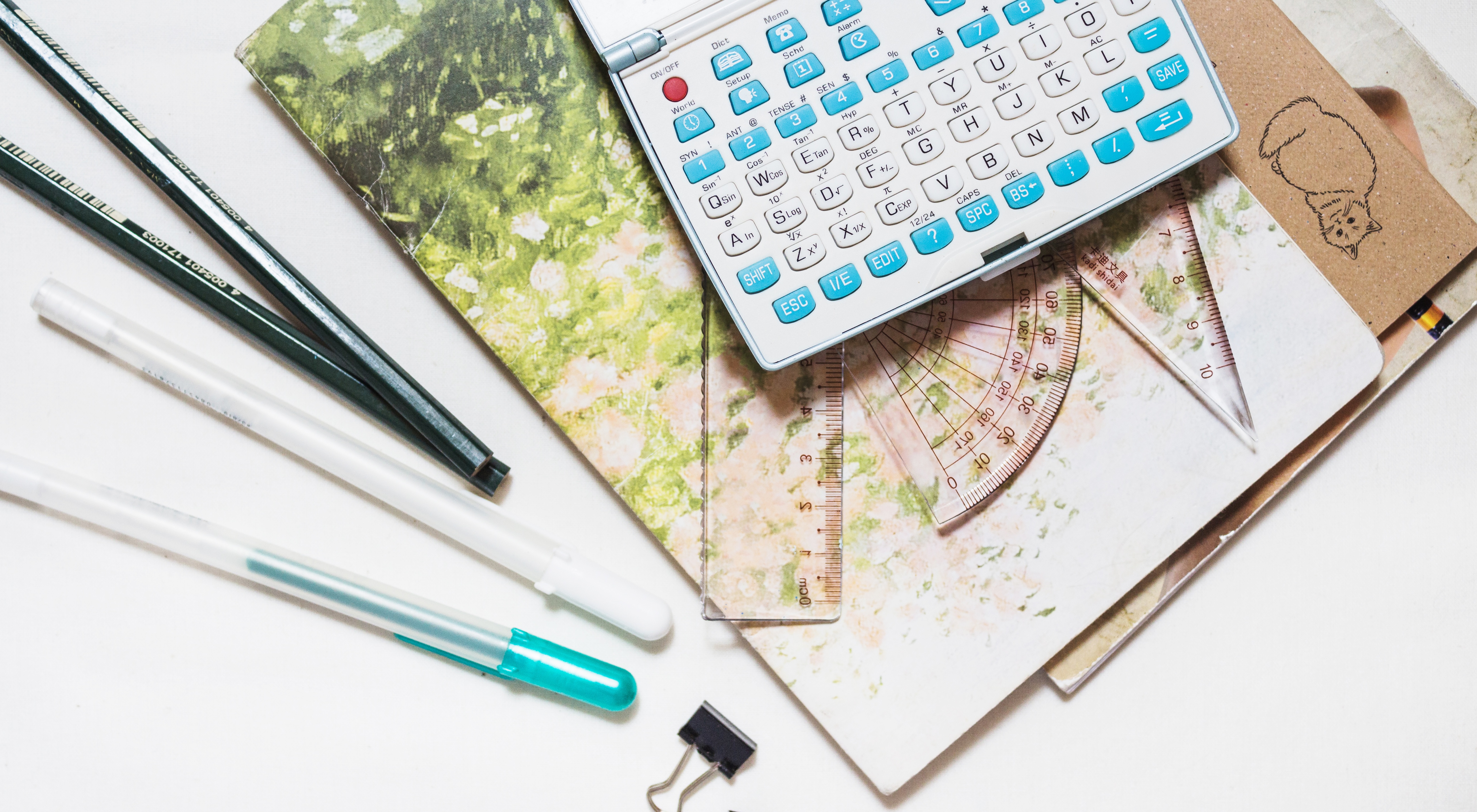 Collage aus Stiften, Heftern, Klammern und einem Taschenrechner.