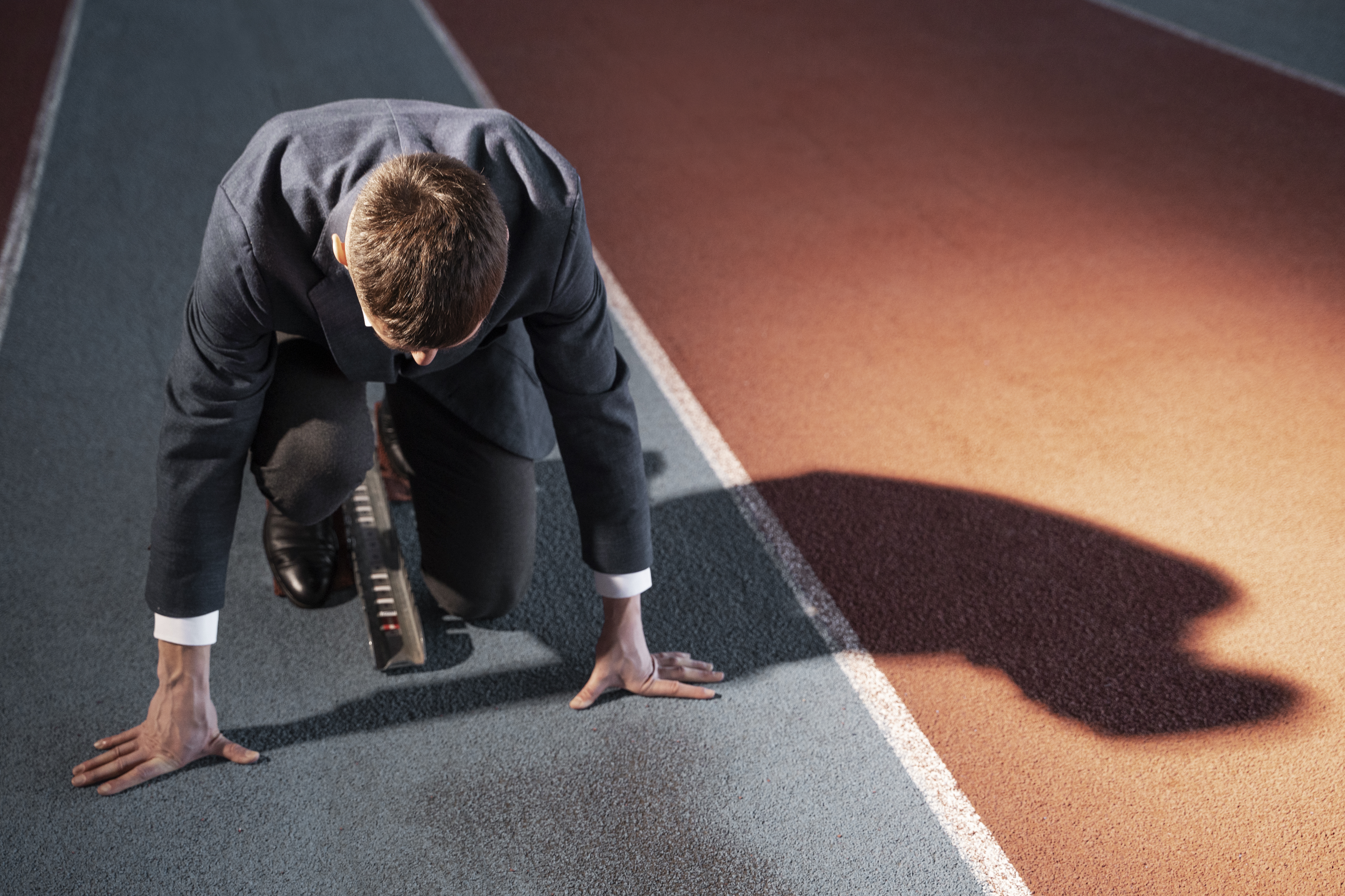 Mann im Anzug, startbereit zum Sprint.