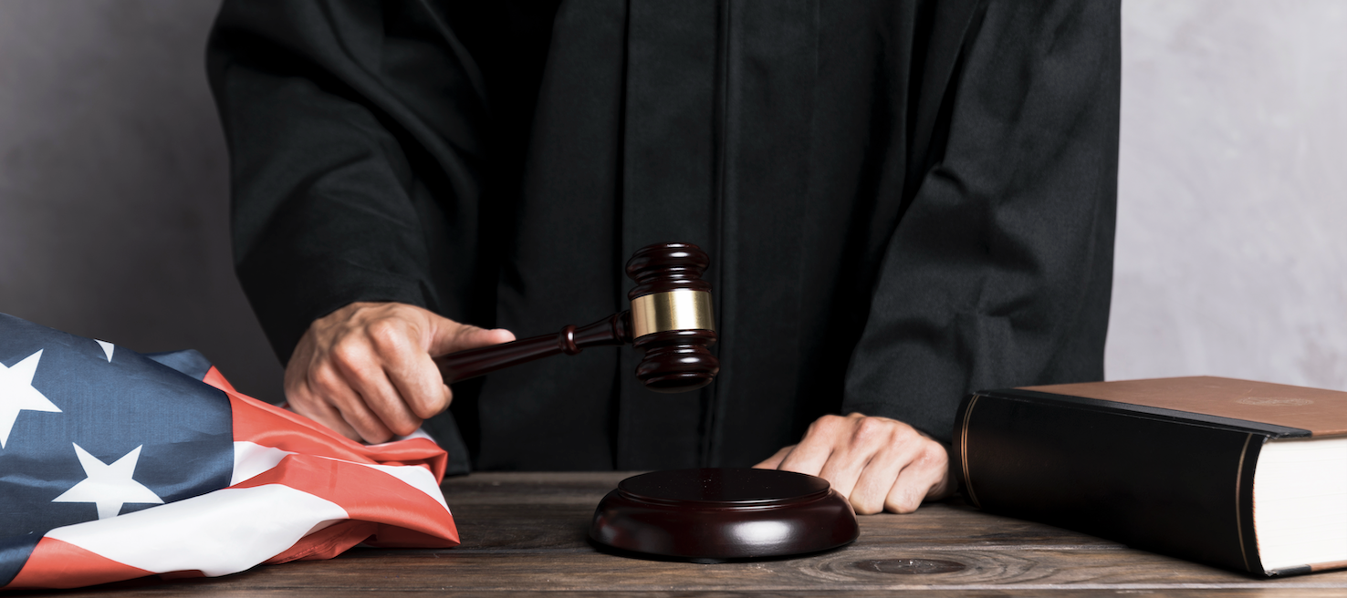 Close-Up Richter schlägt Hammer, amerikanische Flagge und Gesetzbuch.