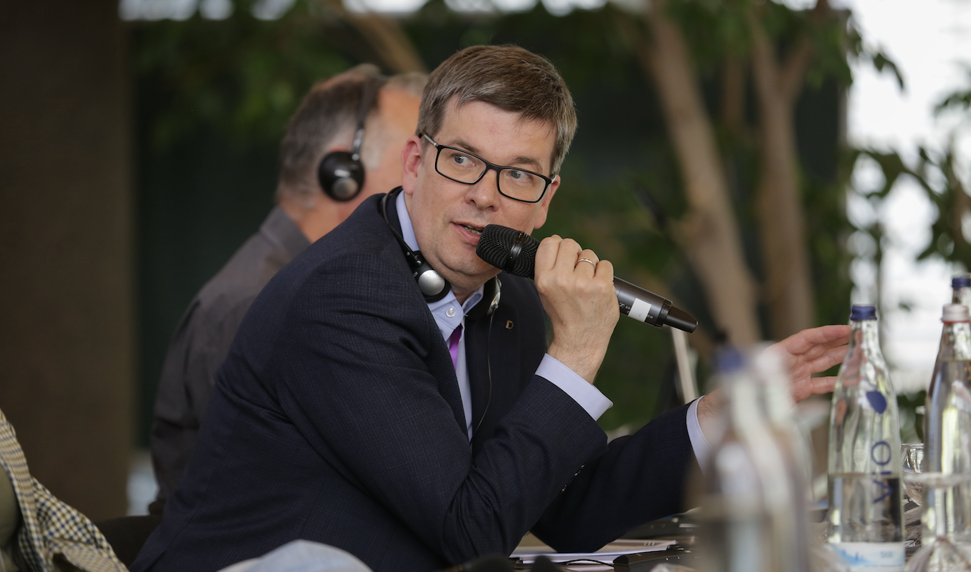 Aufnahme von Matthias Anbuhl mit Mikrofon an Konferenztisch.