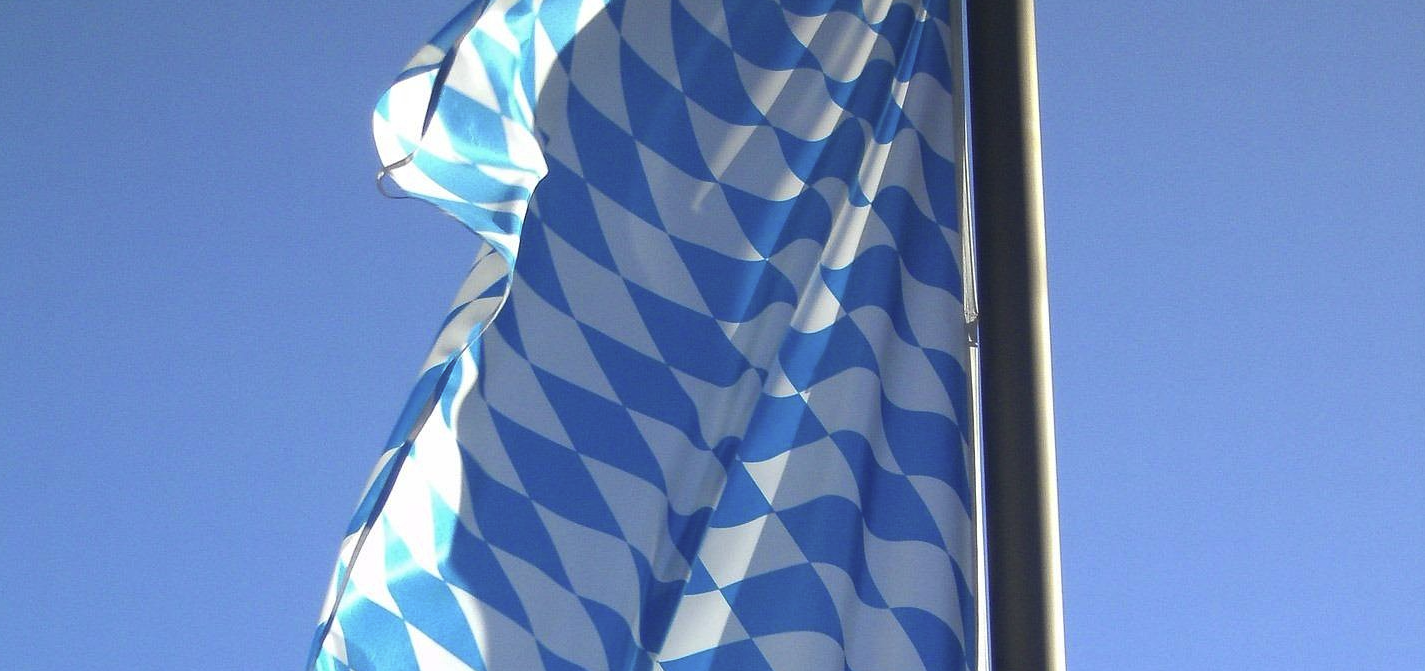 Ausschnitt einer Bayerischen Flagge, die vor blauem Himmel weht.