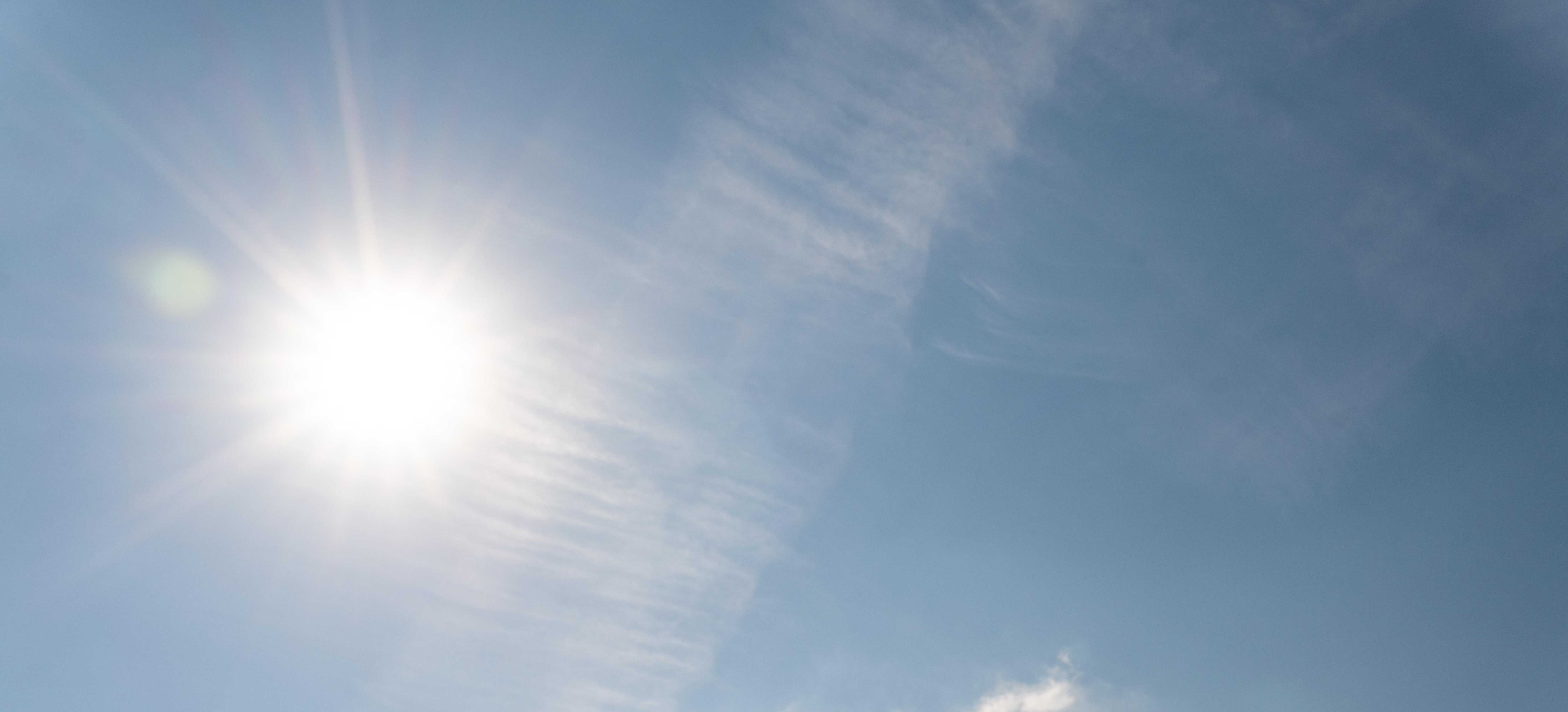 Sonne am blauen Himmel mit einzelnen Wolkenschleiern.