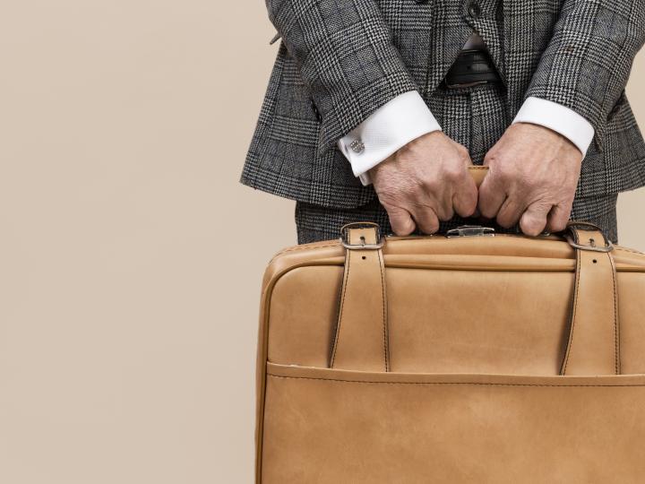 Mann im Anzug hält eine Lederbrieftasche.