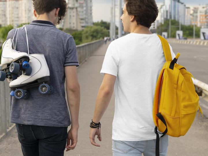 Zwei Freunde verbringen draussen Zeit zusammen, einer mit Rucksack, der andere mit Rollschuhen.