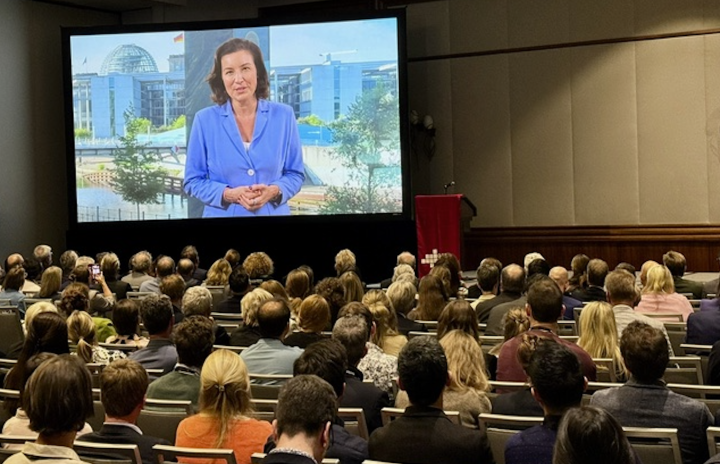Uebertragung eines Grusswortes von Dorothee Baer ueber Leinwand in einem Vortragssaal bei der GAIN Konferenz 2025.