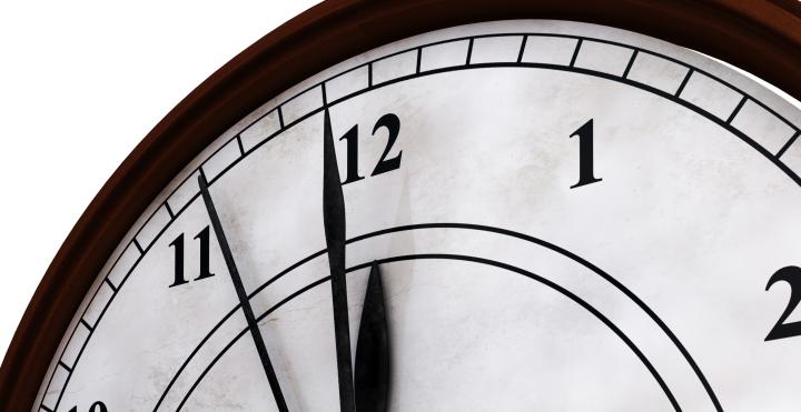 Ausschnitt einer Uhr, die Zeiger stehen auf kurz vor zwoelf. 