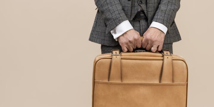 Mann im Anzug hält eine Lederbrieftasche.