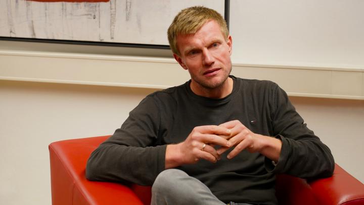 Marcel Helbig im Gespraech, in einem roten Sessel sitzend.