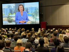 Uebertragung eines Grusswortes von Dorothee Baer ueber Leinwand in einem Vortragssaal bei der GAIN Konferenz 2025.