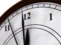 Ausschnitt einer Uhr, die Zeiger stehen auf kurz vor zwoelf. 