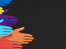 Komposition aus fuenf bunten Haenden aus Papier vor schwarzem Hintergrund.