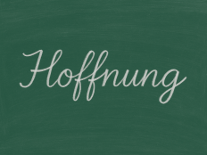 Schultafel, auf der in Schreibschrift mit weisse rKreide das Wort Hoffnung steht.