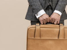 Mann im Anzug hält eine Lederbrieftasche.