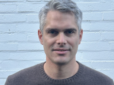Portraitfoto Nils Hansson vor weißer Backsteinmauer.