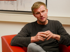 Marcel Helbig im Gespraech, in einem roten Sessel sitzend.