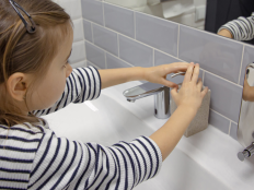 Schuelerin pumpt Seife aus Spender, um Haende zu waschen.