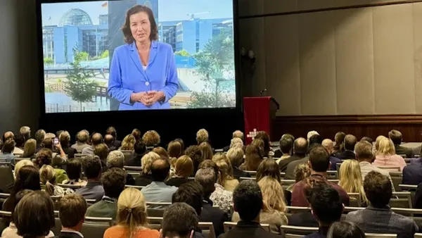 Uebertragung eines Grusswortes von Dorothee Baer ueber Leinwand in einem Vortragssaal bei der GAIN Konferenz 2025.