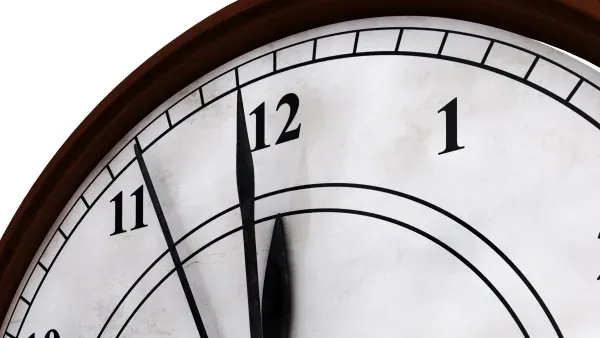 Ausschnitt einer Uhr, die Zeiger stehen auf kurz vor zwoelf. 