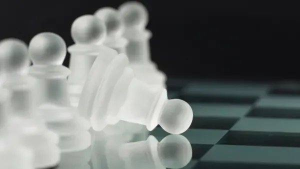 Stilisiertes Schachbrett mit einer Reihe Bauern, ein Bauer ist aufs Spielbrett gekippt.