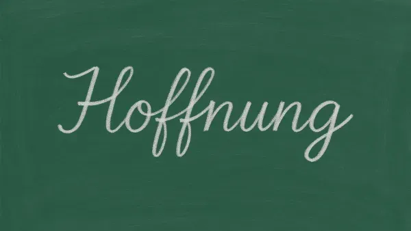 Schultafel, auf der in Schreibschrift mit weisse rKreide das Wort Hoffnung steht.