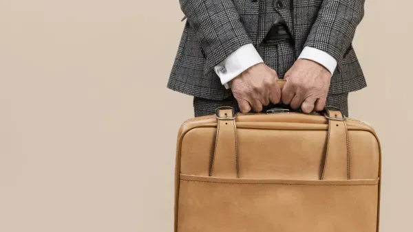 Mann im Anzug hält eine Lederbrieftasche.