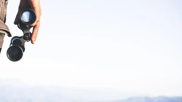 Mann mit Fernglas in der Hand vor weitem Himmel