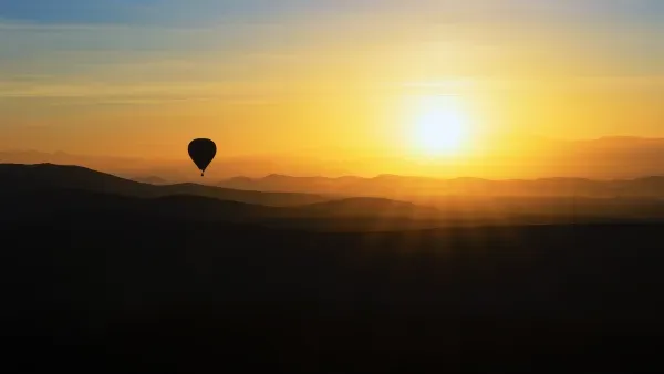 Sonnenaufgang über Hügeln mit Heissluftballon.