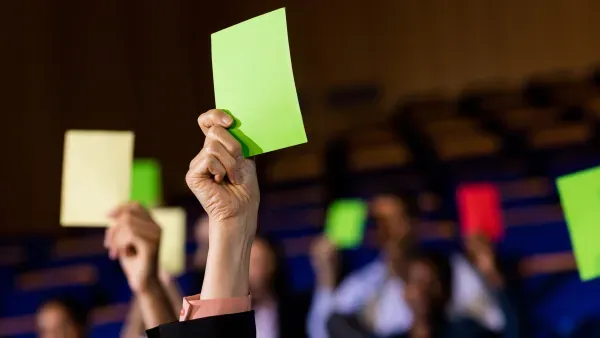 In die Luft gereckte Haende mit gruenen und einer roten Abstimmungskarte.