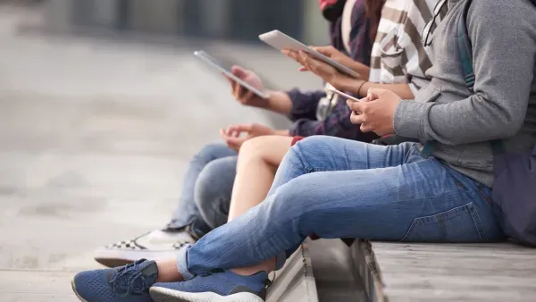 Jugendliche sitzen draussen nebeneinander und nutzen ihre Smartphones.