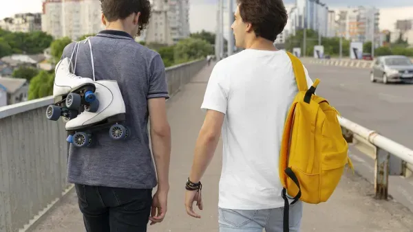 Zwei Freunde verbringen draussen Zeit zusammen, einer mit Rucksack, der andere mit Rollschuhen.