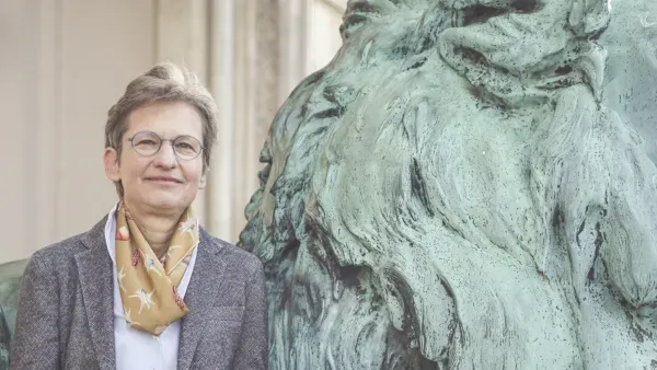 Portraitfoto Eva Barloesius, an steinernen Loewen gelehnt.